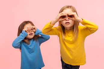 Adorable, curious, nosy two little girls looking through fingers imitating binoculars, exp