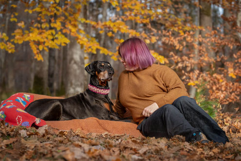 Hundefotografie: Eine Frau mit ihrem Dobermann im herbstlichen Wald