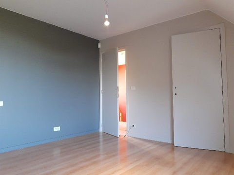 Leeg appartement met grijze en beige muren, houten vloer en open deur.