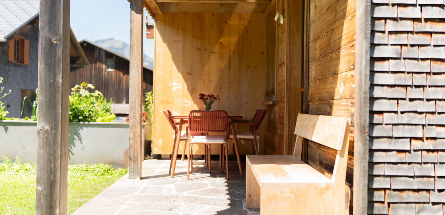 Sonnige Terrasse mit Tisch, Stühlen und Bank