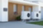 Two white heat pumps outside modern home