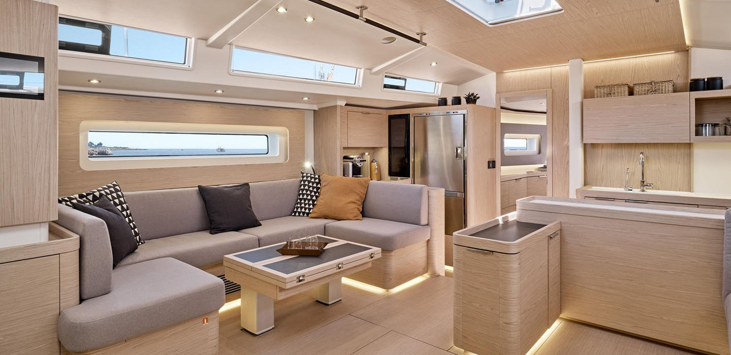 Eleganter Salon einer Luxusyacht mit hellen Holzakzenten, Sofa und moderner Küche