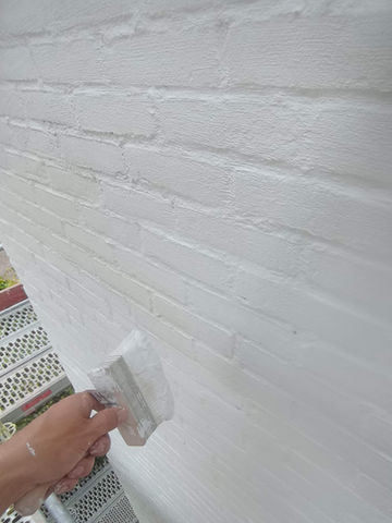 Witte bakstenen muur wordt geverfd met een spatel