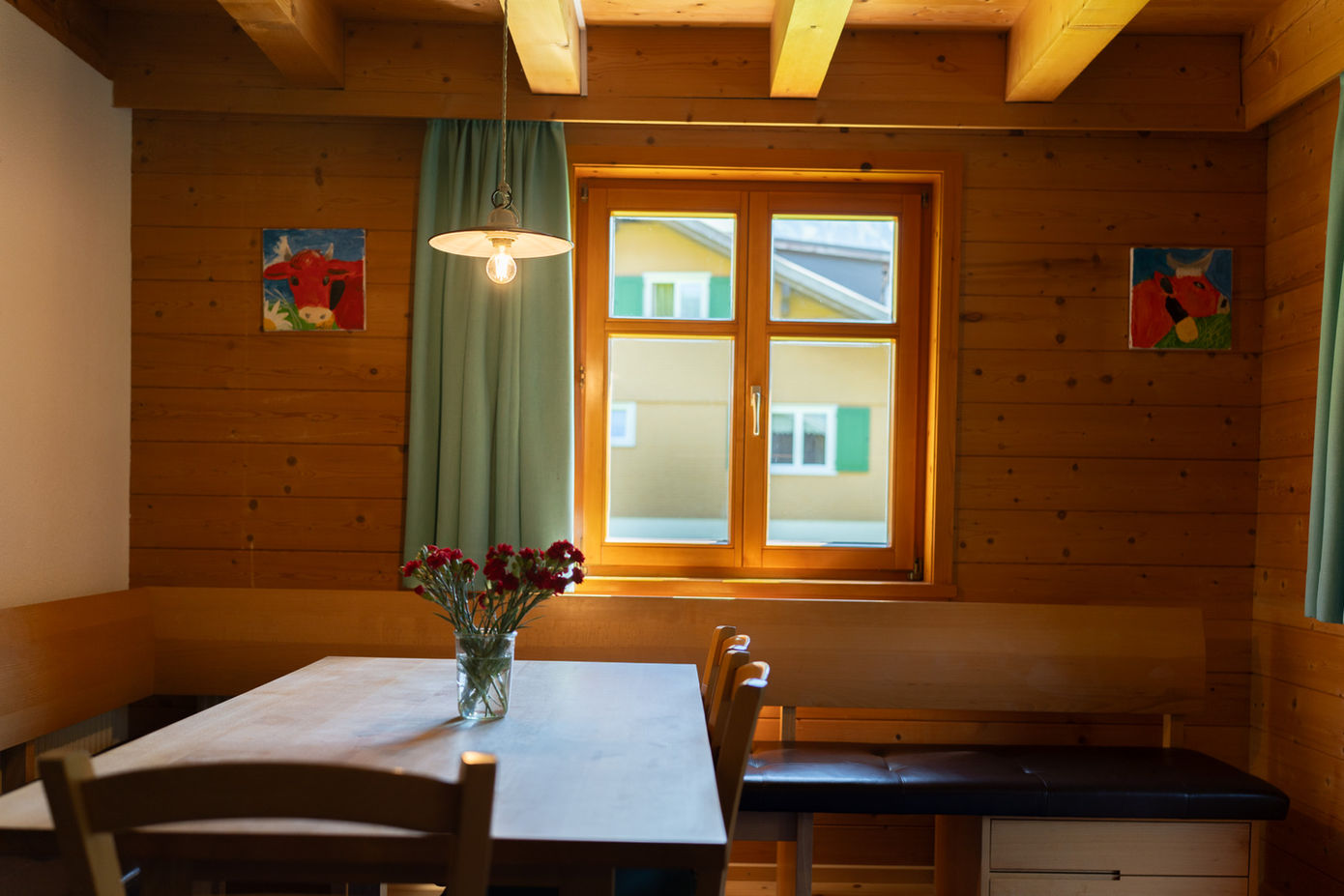 Holzhaus-Essbereich mit Tisch, Blumen und Fensterblick