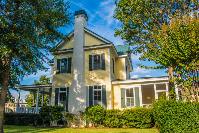 Side view of yellow southern style house with chimney, front porch and screened porch
