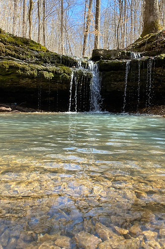 Jolie petite cascade tombant dans une bassine naturelle d'eau clair inspirant la paix profonde et un sentiment de purification énergétique