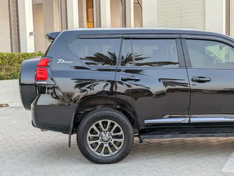 Miniature : SUV noir garé, badge 70ème, reflets de palmiers sur la carrosserie.