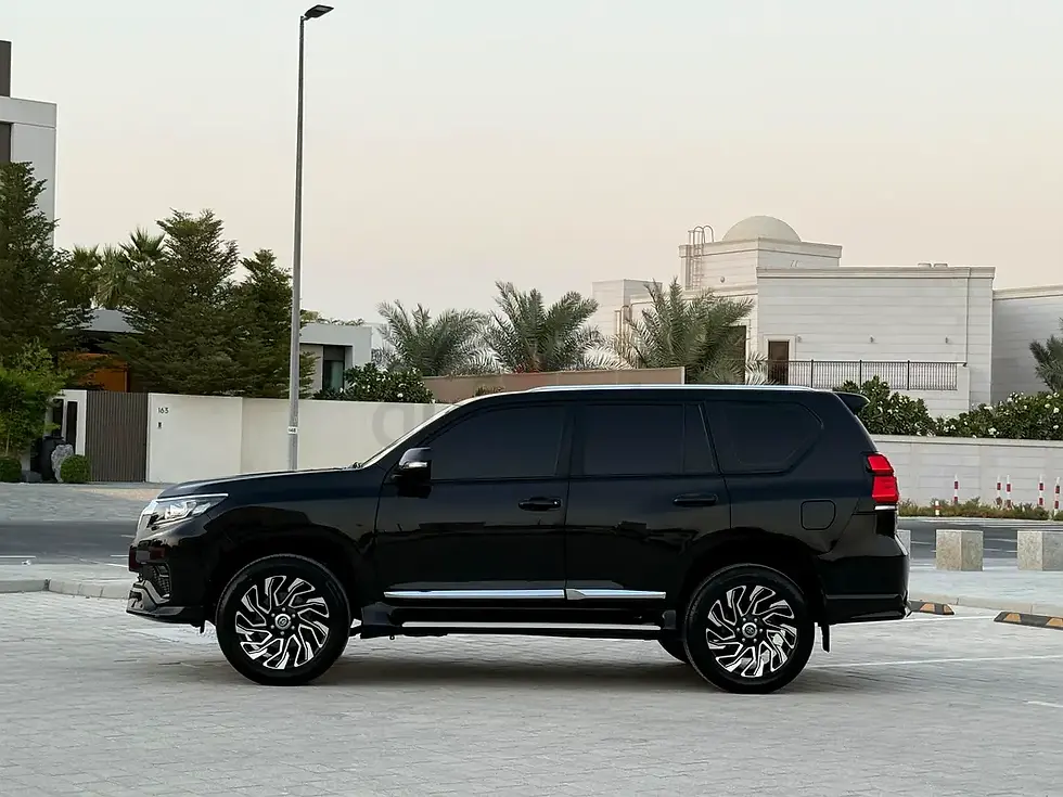 Miniature : Grand SUV noir brillant garé, bâtiments modernes en arrière-plan.