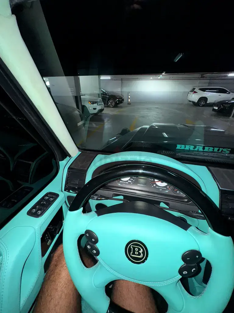 Miniature : Intérieur Brabus turquoise, volant, tableau de bord, vue parking souterrain.