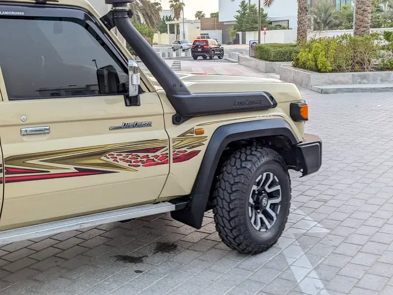 Miniature : SUV beige avec tuba et pneus tout-terrain sur rue pavée.