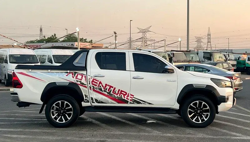 Miniature : Côté d'un pick-up blanc Toyota Hilux avec autocollant ADVENTURE.