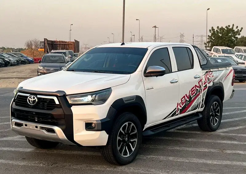 Miniature : Toyota Hilux blanche REVO ADVENTURE stationnée sur un parking extérieur.