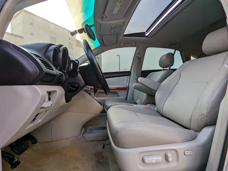 Intérieur de voiture, sièges en cuir clair, tableau de bord, toit ouvrant panoramique.