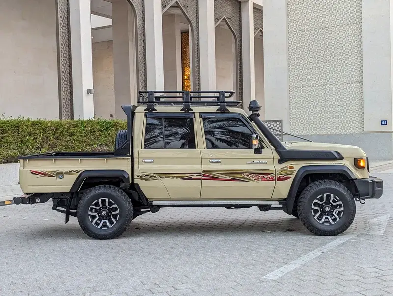 Miniature : Camionnette tout-terrain beige, galerie toit, snorkel, devant bâtiment moderne.