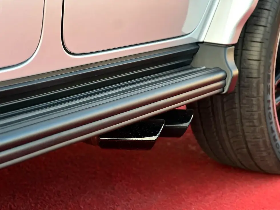 Miniature : Marchepied latéral noir et doubles échappements d'un véhicule sur tapis rouge.