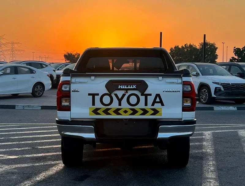 Miniature : Vue arrière pick-up Toyota Hilux blanc avec logos HILUX TOYOTA au coucher.