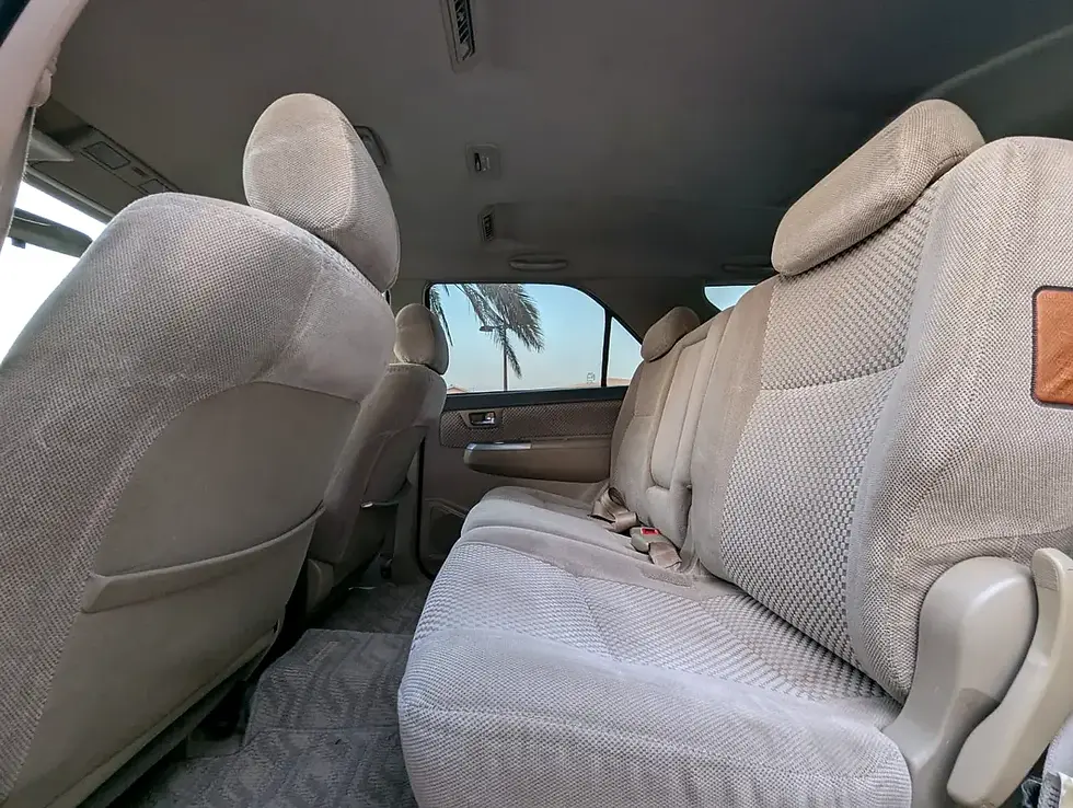 Miniature : Intérieur de véhicule, sièges arrière en tissu beige avec palmier visible.