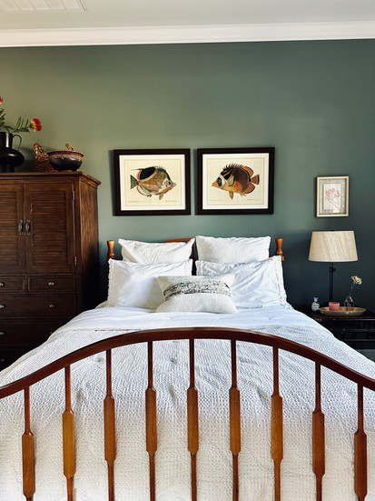 California-coastal bedroom with wood spindle bed, white bedding, and antique fish illustrations on green walls.