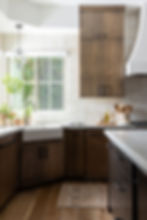 Kitchen featuring layered lighting with a statement pendant over the sink, natural daylight, and warm wood cabinetry creating depth and balance.