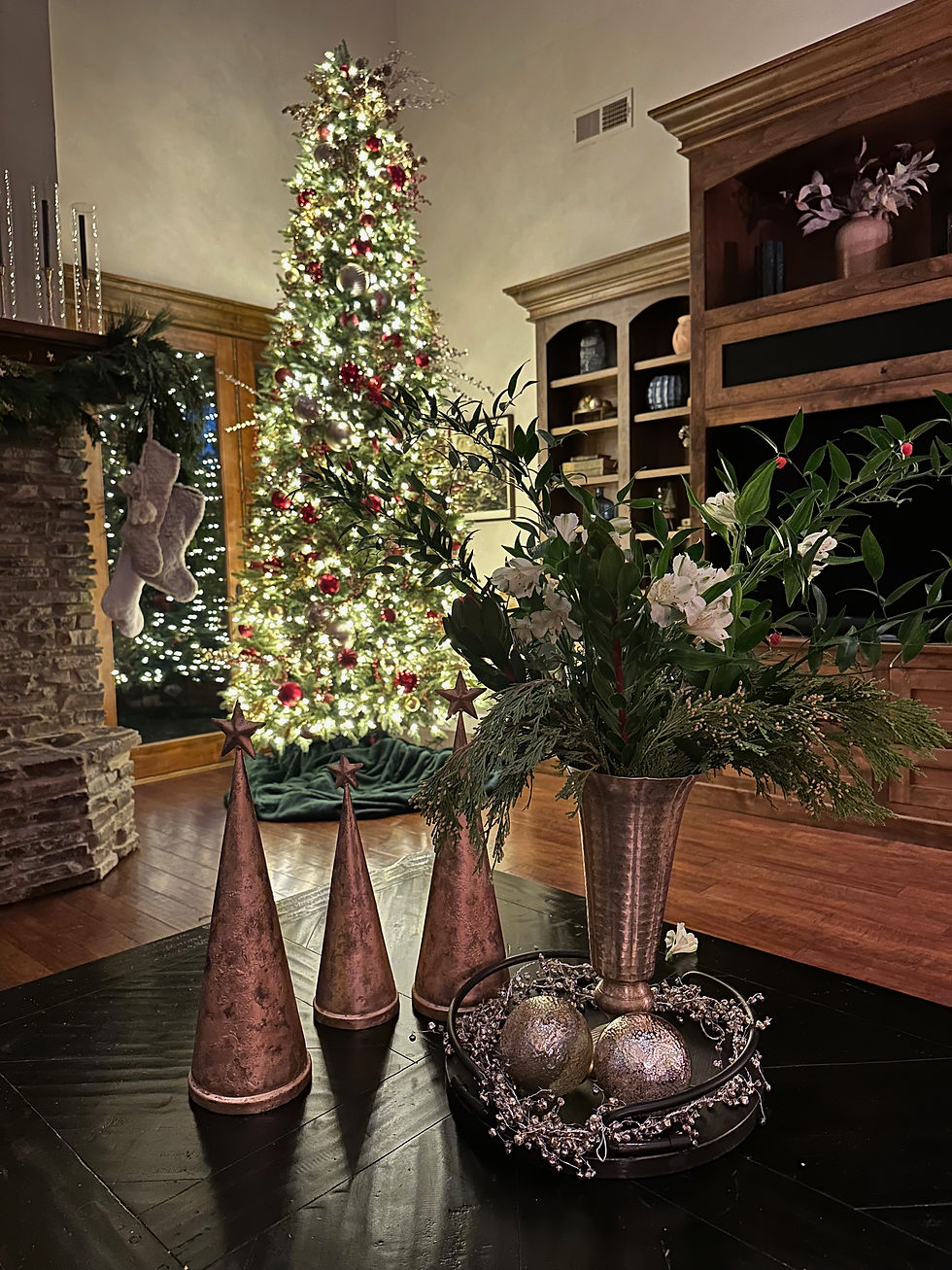 tall christmas tree red balls with white lights white stocking on fireplace, christmas florals, gold decor on coffee table