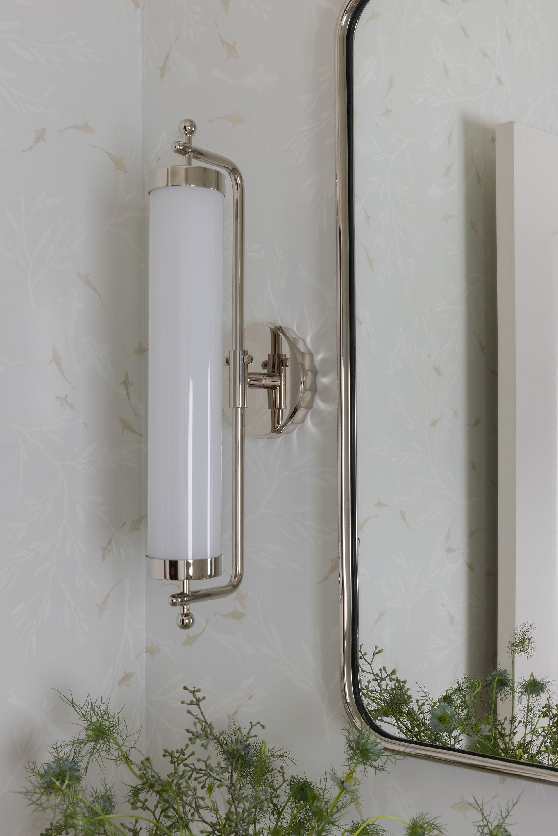 Close up of a bathroom light fixture with a wall-mounted mirror