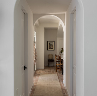Arched hallway with natural light, warm flooring, and architectural detailing creating depth and visual flow throughout the home.