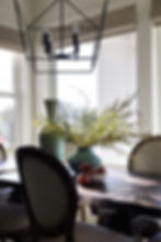 Dining room showcasing statement overhead lighting balanced with abundant natural light to create a layered lighting plan.
