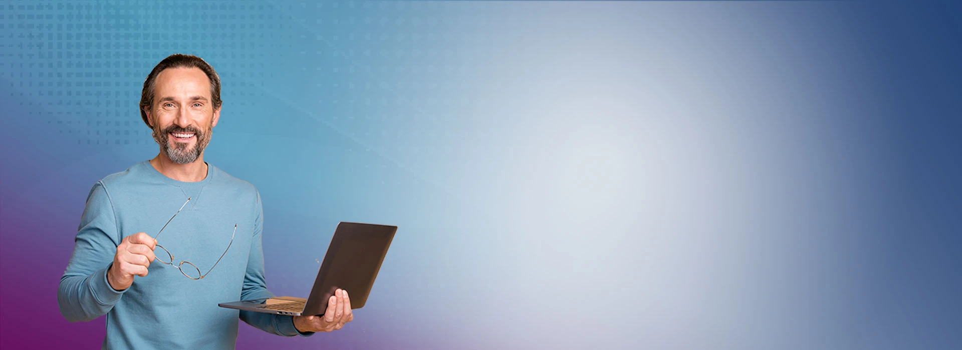 Smiling male holding a laptop and glasses.
