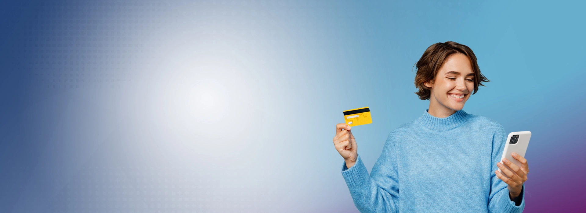 Smiling female holding a credit card and looking at her cell phone.
