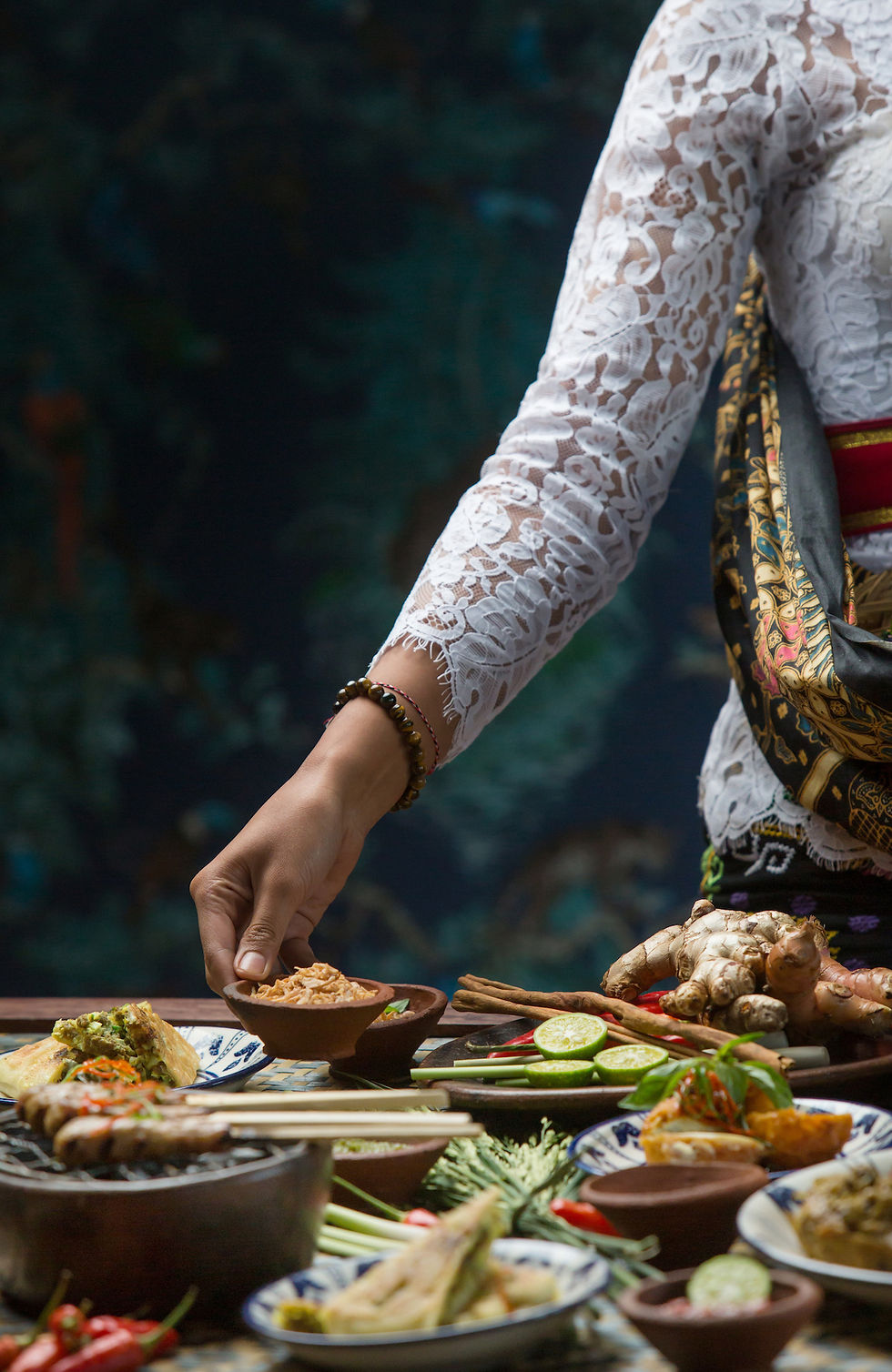 Balinese woman sets the table with traditional sauce made from lemongrass ginger and lime