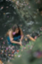 woman during purification ritual melukat in bali during niskala tour staying in holy spring and pool surrounded by flowers and petals happy