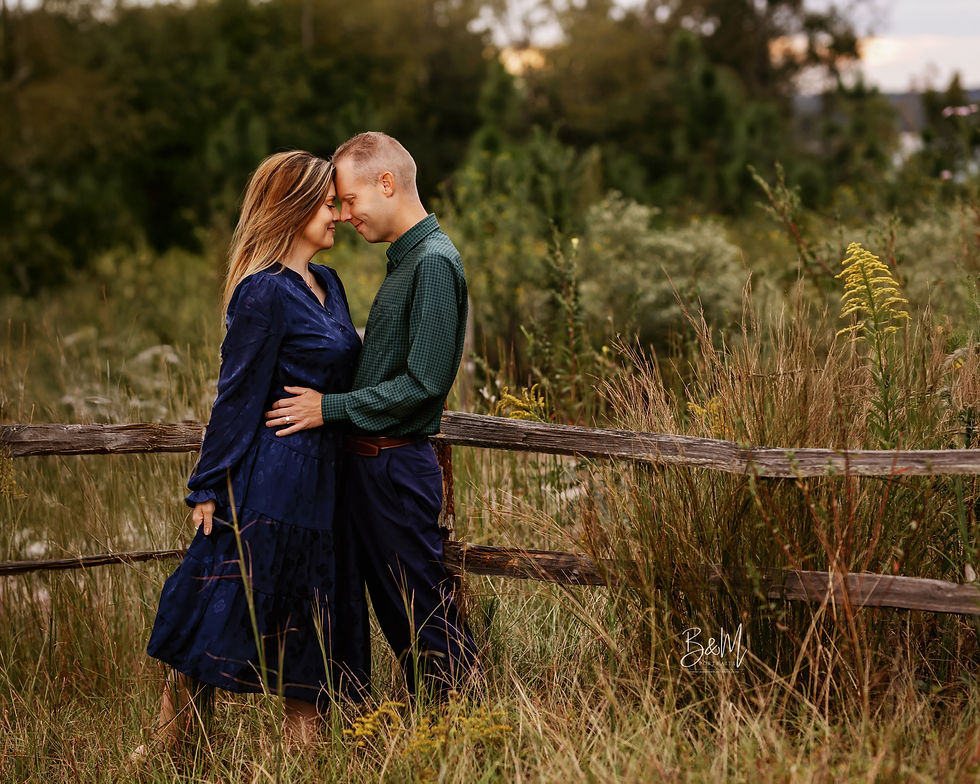 A couple holds hands, walking through a field of christmas trees at sunset. She wears a green dress; he wears a beige sweater. The mood is serene.