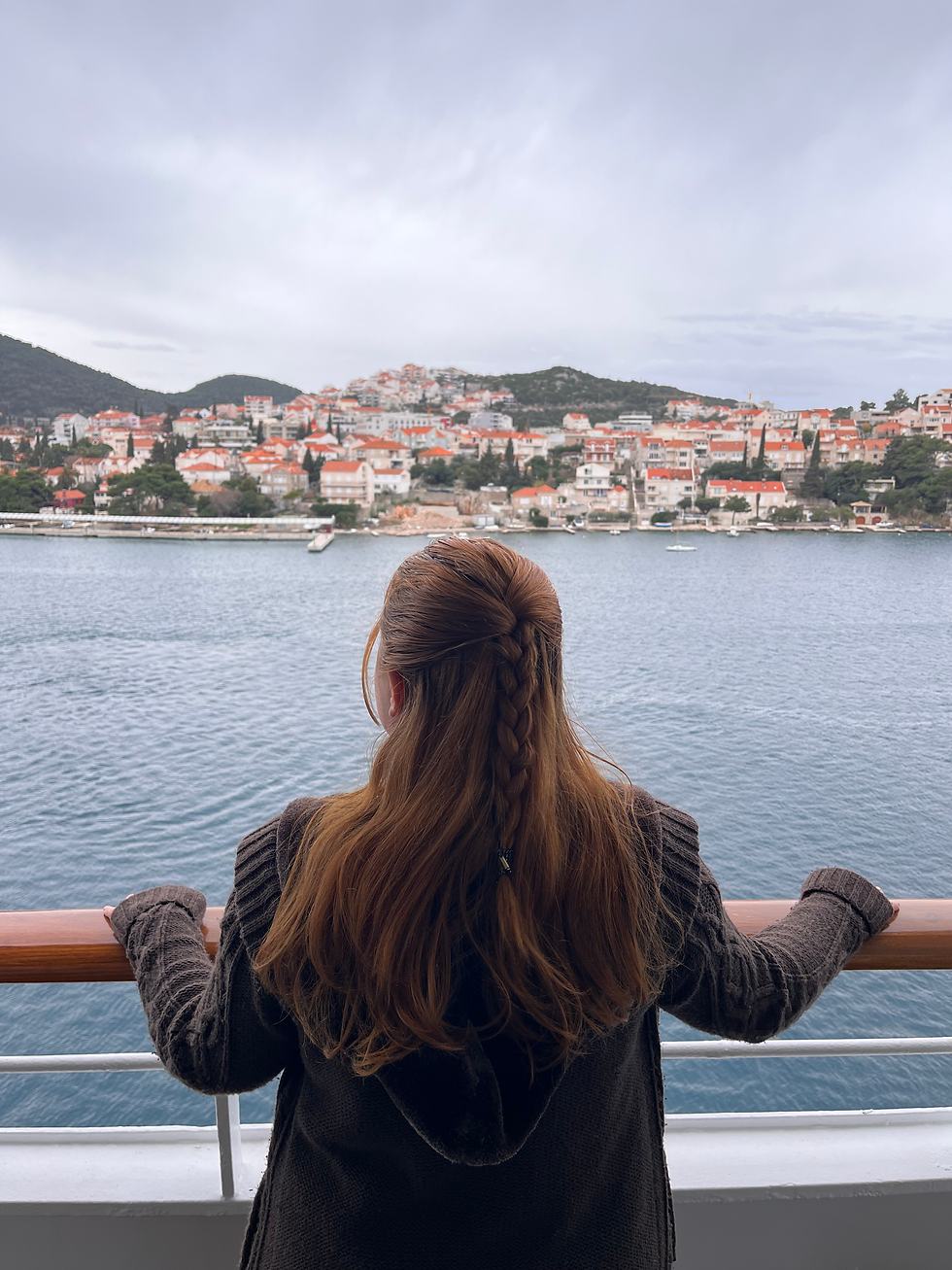 The author standing on the ships railings, looking out to the town of Dubrovnik as the ship makes its way to shore. The author has her hair tied in a long plait, similar to that of Sansa Starks hair style from game of thrones