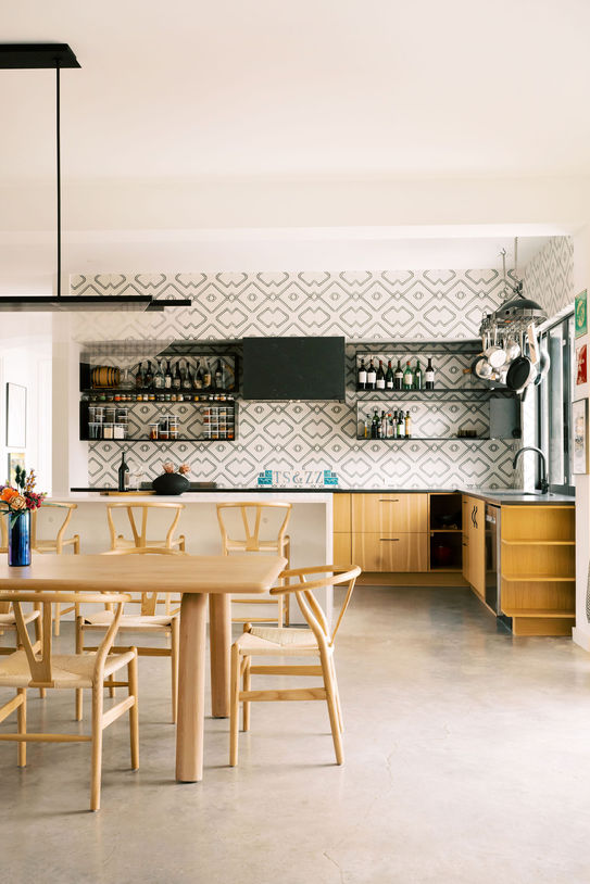 Open-concept dining area with wood table, wishbone chairs, and a sculptural pendant light in an Austin wabi sabi home