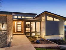 A one-story home with a concrete entryway, accent lights on the exterior walls, and multiple small windows.