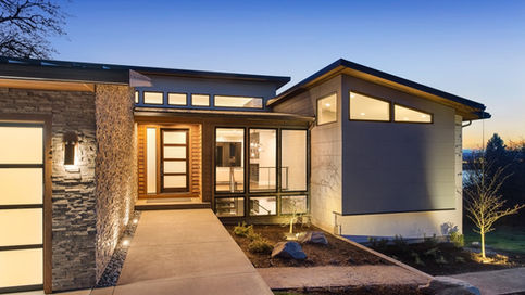A one-story home with a concrete entryway, accent lights on the exterior walls, and multiple small windows.