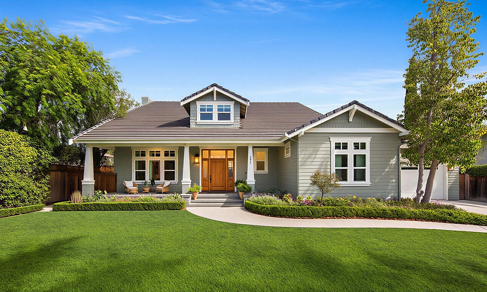 Modern gray suburban home with a welcoming front porch, wood entry door, manicured lawn, and neatly landscaped garden beds.