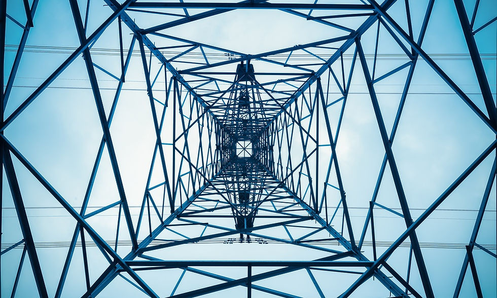 Looking up through a steel transmission tower. Geometric beams form a symmetrical pattern against the open sky.
