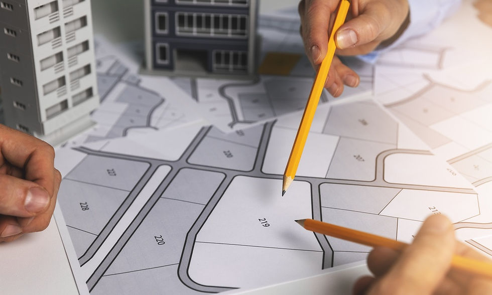 Two people are resting their hands on a diagram of an urban development location. Both people are holding pencils.