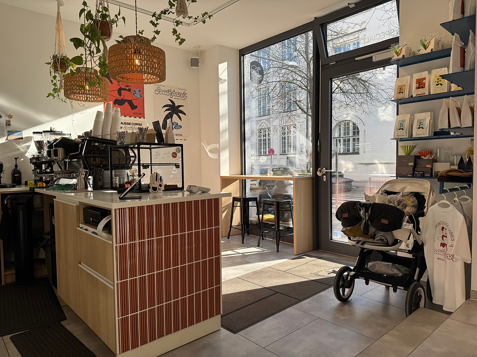 Bright interior of Southbank Specialty Coffee in Munich featuring an espresso bar, woven pendant lights, and a street view.