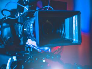 Professional Video Production. Close-up of a camera setup, focus on the lens and operator's hand adjusting settings; futuristic ambiance.