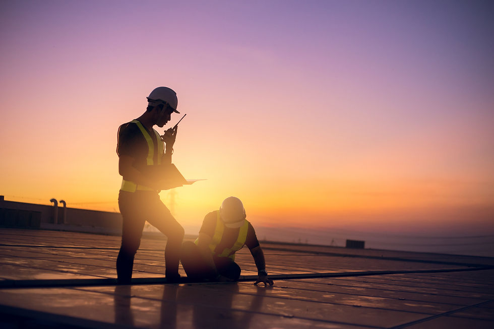 Two construction workers in hard hats on a roof at sunset, one holding a walkie-talkie and clipboard. Vibrant orange and purple sky.