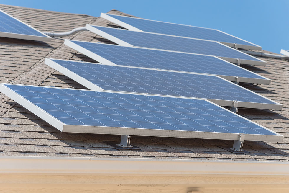 Solar panels on a residential roof under a clear blue sky. Panels are aligned in rows, angled for optimal sun exposure. Mood is sunny and calm.