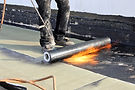Superior Roofing crew patching flat roof membrane