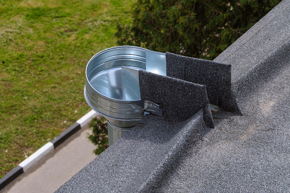 Metal roof vent with black flashing on gray shingles beside a grassy yard and road, outdoors in daylight