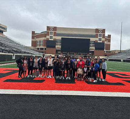 Large group posing on a red football field end zone.