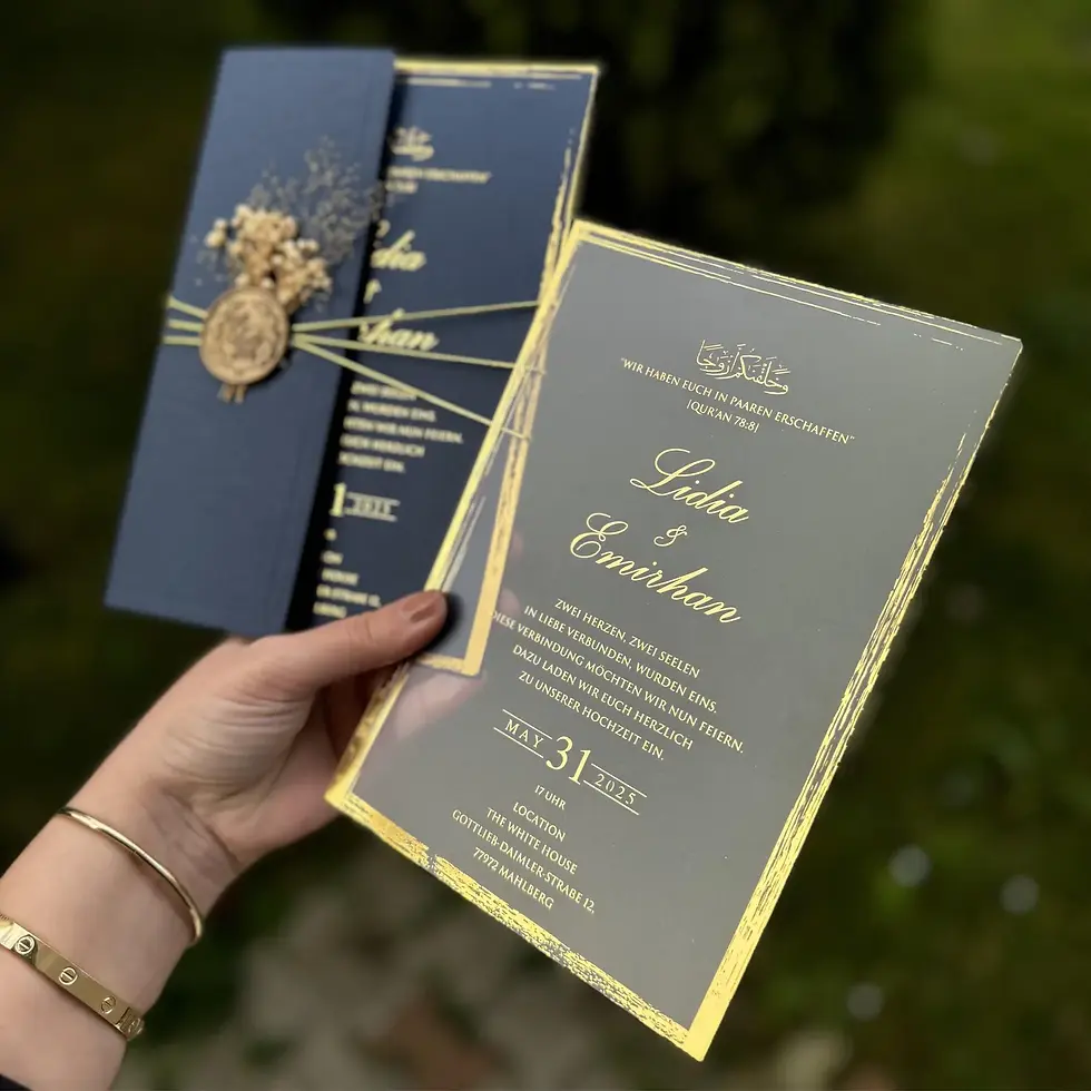 Hand holding wedding invitation with gold text. 