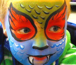Young boy with a green red and blue Dinosaur Monster Face Painting on his face