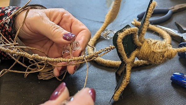 picture of a ladies hands making a floral craft using wire, twine and a small decorative glass test tube