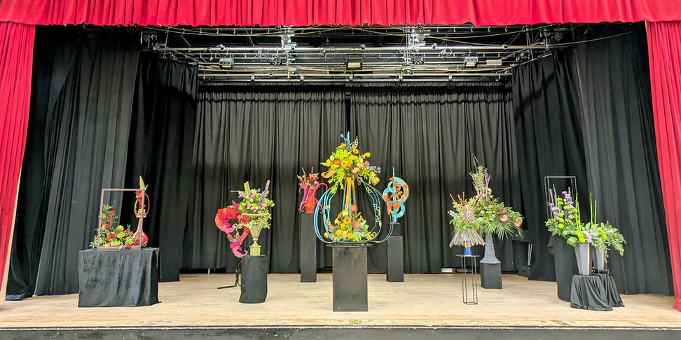 Theatre stage with floral arrangements on black pedestals